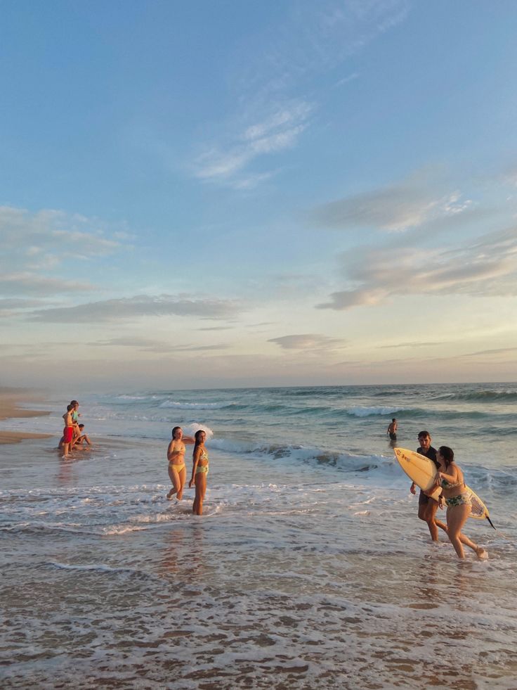 some people are walking in the water with surfboards and one person is holding a surfboard