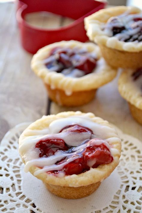 small pies with icing and strawberries are on a doily