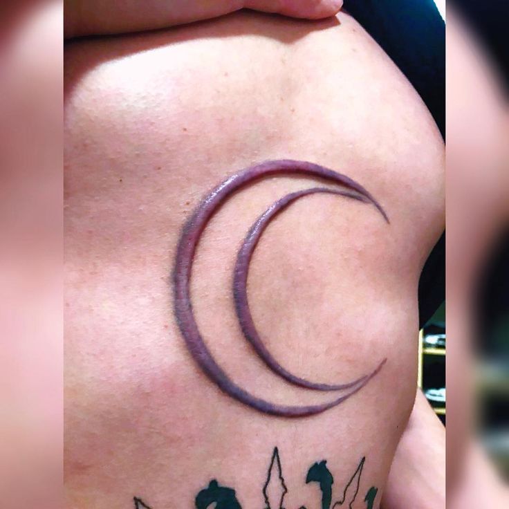 a woman's lower back tattoo with cats and the moon