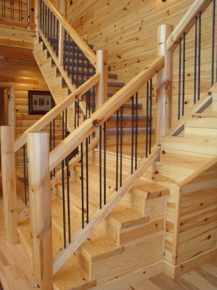 the inside of a log cabin with stairs and railings