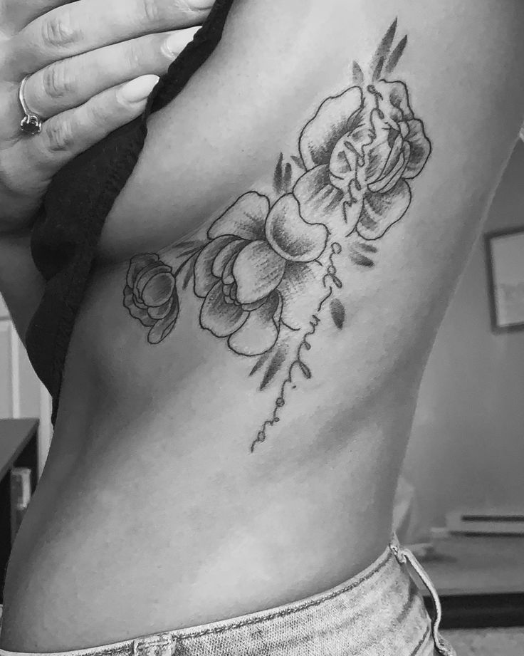 a black and white photo of a woman's stomach with flowers tattooed on it