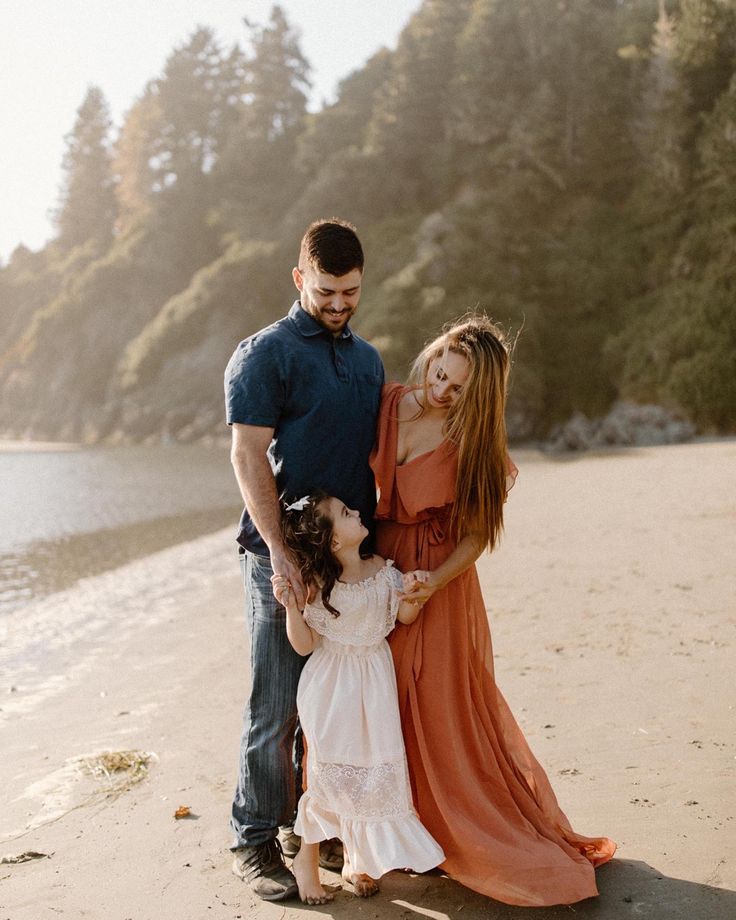 a man and woman standing on the beach with their two children