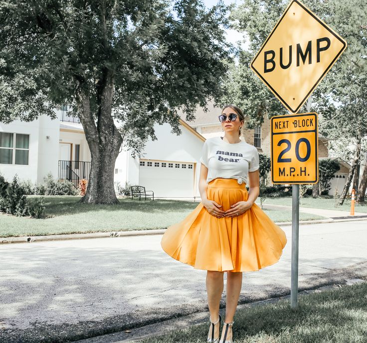 a woman standing next to a bump sign in front of a road with her hands on her hips