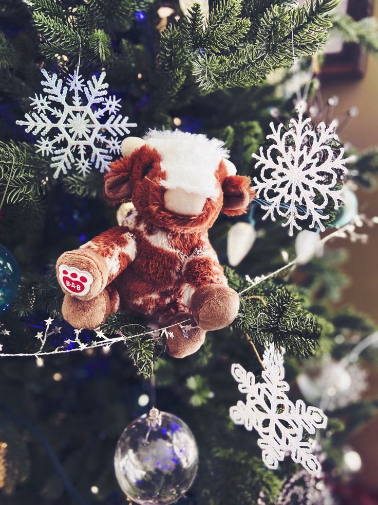 a teddy bear hanging from the top of a christmas tree