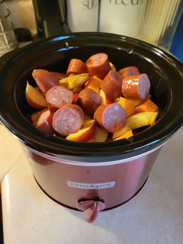 a crock pot filled with sausage and potatoes