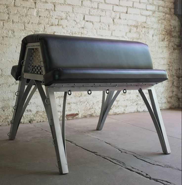 a black bench sitting in front of a brick wall