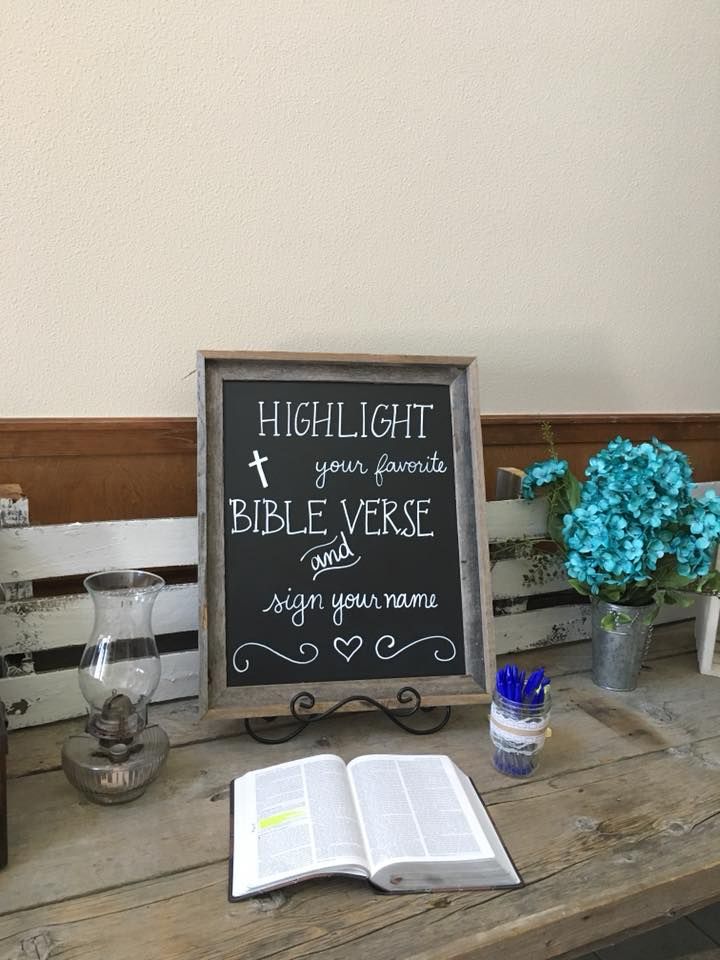 a table topped with a bible next to a vase filled with flowers and an open book