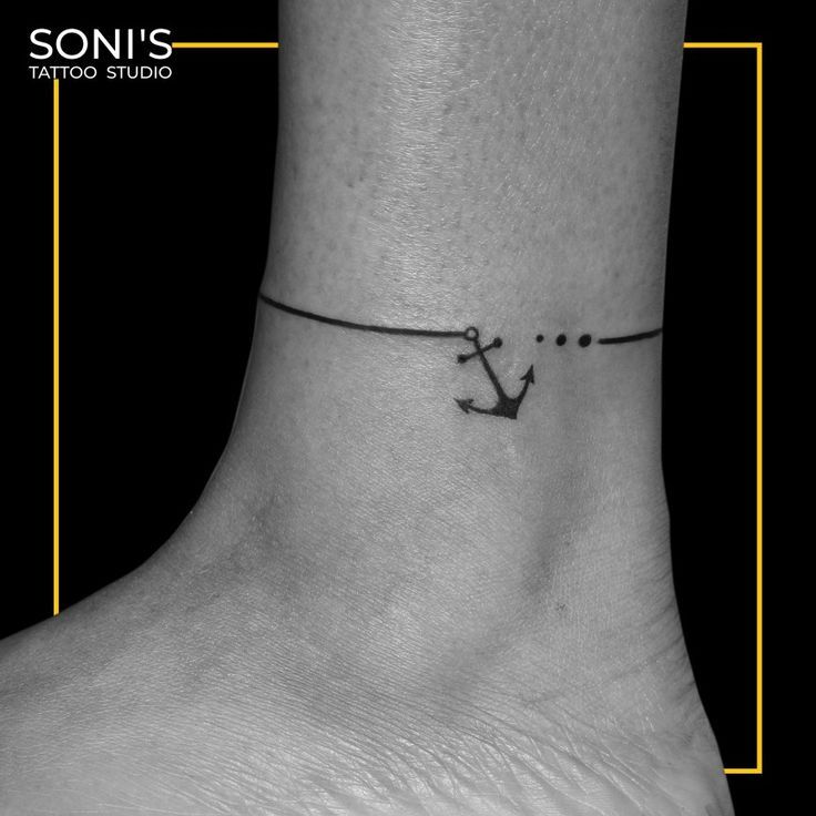 a black and white photo of a small anchor tattoo on the ankle, with an inscription that reads son's tattoo studio