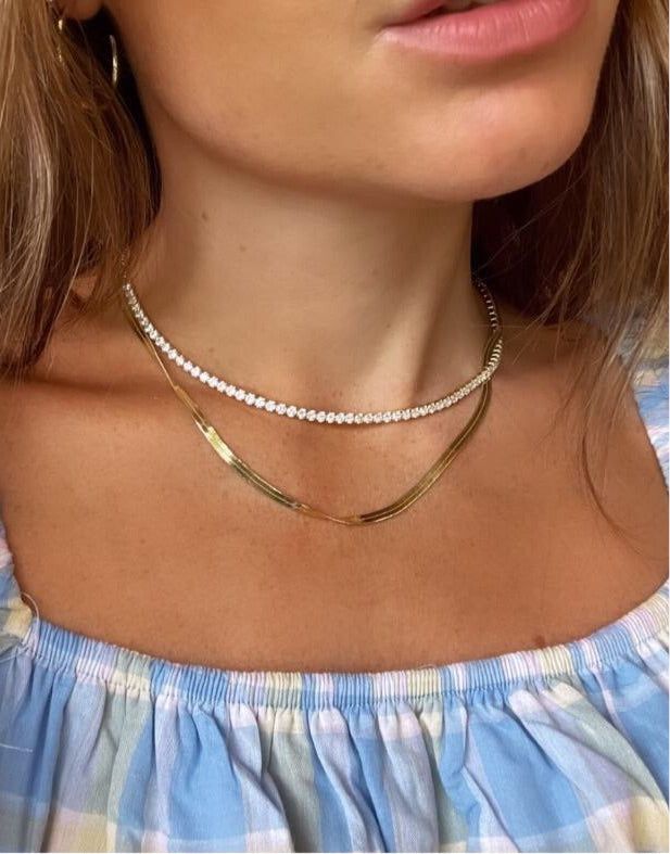 Our luxurious, best selling tennis necklace with a high end feel and finish. 3mm grade A cubic zirconia, diamond cut.  2 micron gold plated. Made to last.  With our monogram tag. Comes in our monogram box. How to take care of your C&Co. items  We advise to store your pieces individually in their box so they don't scratch, rub off or get in a tangle.  Try avoid extreme heat or humidity as this may cause your items to tarnish.  We do recommend when dressing to put your jewellery on after you use p Dazzling Cubic Zirconia Tennis Necklace For Everyday Luxury, Everyday Luxury Cubic Zirconia Tennis Necklace, Gold Tennis Necklace With Diamond Accents As A Gift, Gold Cubic Zirconia Tennis Necklace Gift, Dainty Gold Diamond Tennis Necklace, Gold Tennis Necklace With Brilliant Cut For Everyday Luxury, Gold Cubic Zirconia Tennis Necklace For Anniversary, Gold Brilliant Cut Tennis Necklace For Everyday Luxury, Minimalist Cubic Zirconia Tennis Necklace As Gift