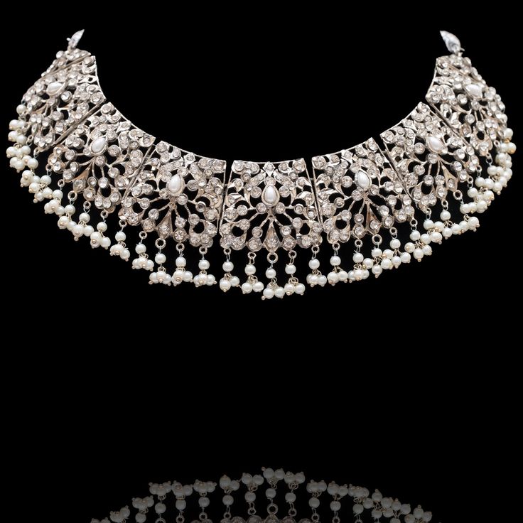 Glow with elegance and beauty! Stunning set boasting a palette crafted entirely of CZ stones and pearl moti. The set includes a necklace, a maang teekah and a pair of earrings. Silver-plated on high-quality brass as base metal. Made by order. Kindly allow 5-7 weeks for the delivery of this item. For custom or urgent requests, please contact support@alacouture.com. *Please Note: We use faux stones and beads in all of our jewelry. Silver Pearl Necklace With Intricate Design, Elegant Hand Set Pearl Necklace For Ceremonial, Elegant Hand Set Pearl Necklace For Ceremonial Occasions, Elegant Hand-set Pearl Necklace For Ceremonial Occasions, Elegant Ceremonial Pearl Jewelry, Festive Silver Jeweled Jewelry Sets, Festive Jeweled Silver Jewelry Sets, Pearl Jewelry With Tilla For Reception, Elegant Pearl Necklace With Tilla For Reception