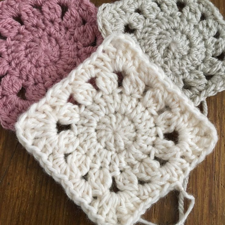 three crocheted squares sitting on top of a wooden table