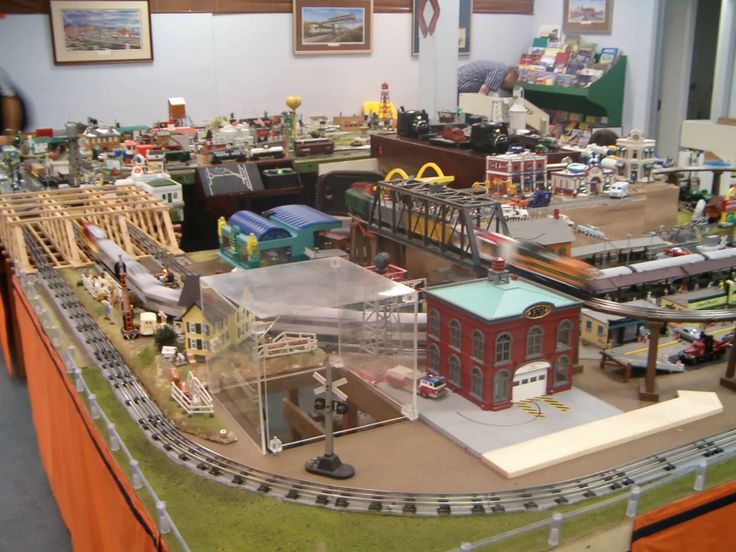 a model train set is on display in a room with other toy trains and buildings