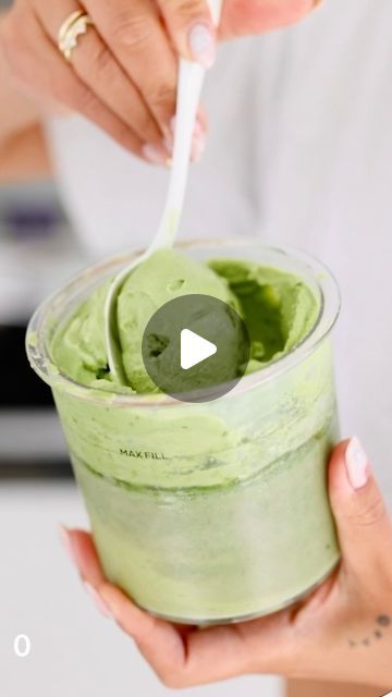 a woman is holding a cup with green food in it and the video below shows how to make this smoothie