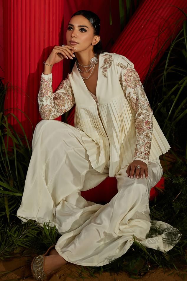 Ivory pleated jacket in georgette and habutai silk base with chintz embroidery using pearls, dabka, sequins, zari,  and beads. Paired with a matching boot-cut sharara and an embroidered slip.
Components: 3
Pattern: Embroidered
Type Of Work: Pearl, Dabka, Sequin, Zari
Neckline: Sweetheart
Sleeve Type: Long
Fabric: Habutai Silk, Georgette, Bamberg Crepe, Dull Lycra, Lining: Heavy Shantoon
Color: Ivory
Occasion: Mehendi and Haldi - Aza Fashions Jacket Sharara, Pleated Jacket, Sharara Set, Ivory Pearl, Embroidered Jacket, Embroidered Silk, Color Ivory, Set For Women, Aza Fashion