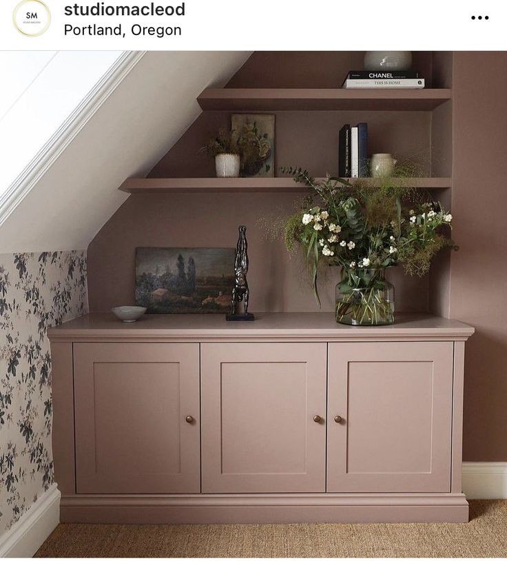 a room with some shelves and flowers on top of the cabinets in front of it