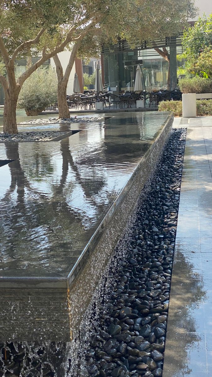 there is a large water feature in the middle of this walkway that leads to an outdoor dining area