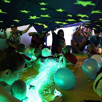 a group of people sitting on the floor with balloons and lights in front of them