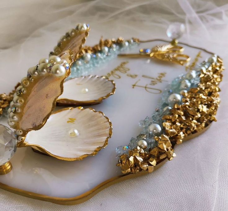 the shell is adorned with pearls and other jewelry pieces on it's side,