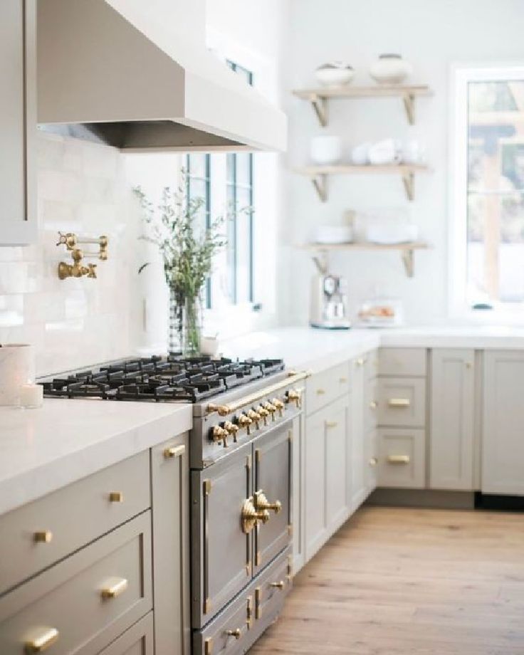 a kitchen with white cabinets and gold knobs on the stove top, along with wooden flooring