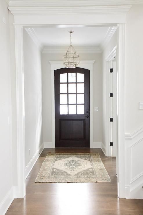 an empty hallway with a black door and rug on the floor in front of it