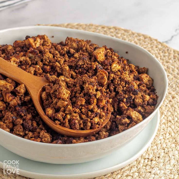 a wooden spoon in a white bowl filled with granola