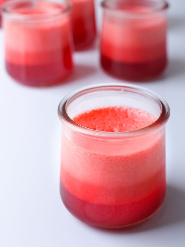 three glasses filled with red liquid sitting on top of a white table next to each other