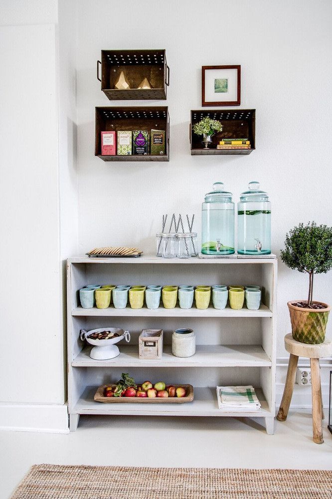 a shelf filled with lots of food on top of a white floor next to a potted plant