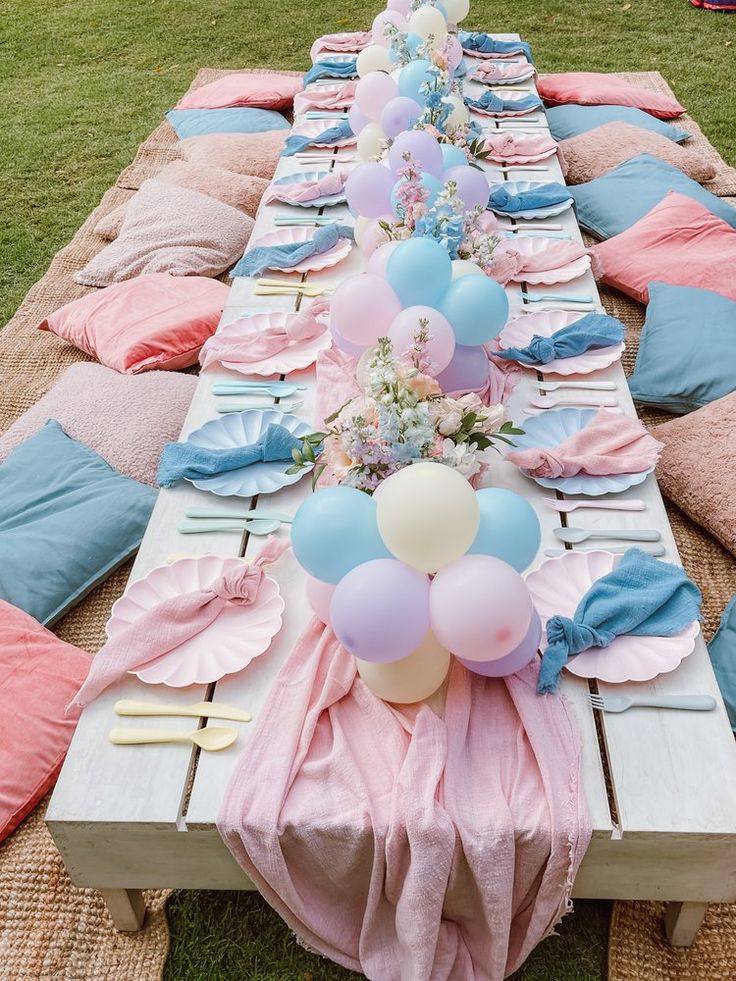 a long table set up with pink, blue and white balloons on top of it