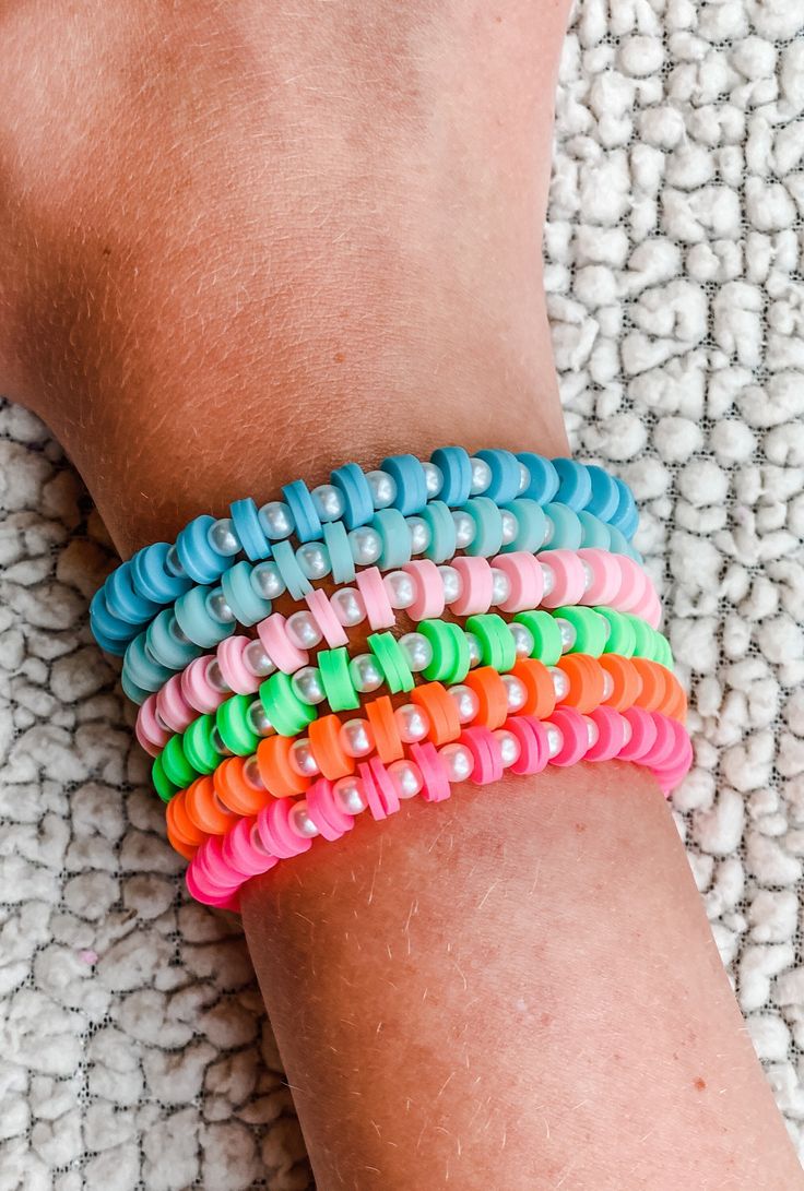 a close up of a person's arm wearing colorful rubber bracelets on top of a rug