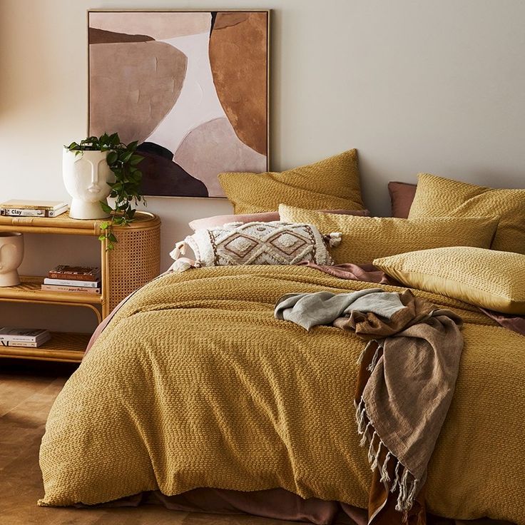 a bedroom with a bed covered in mustard colored linens