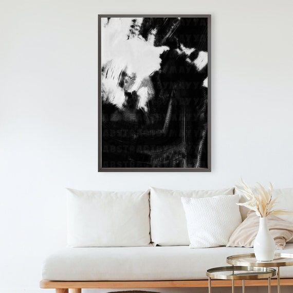 a black and white abstract painting hangs above a couch