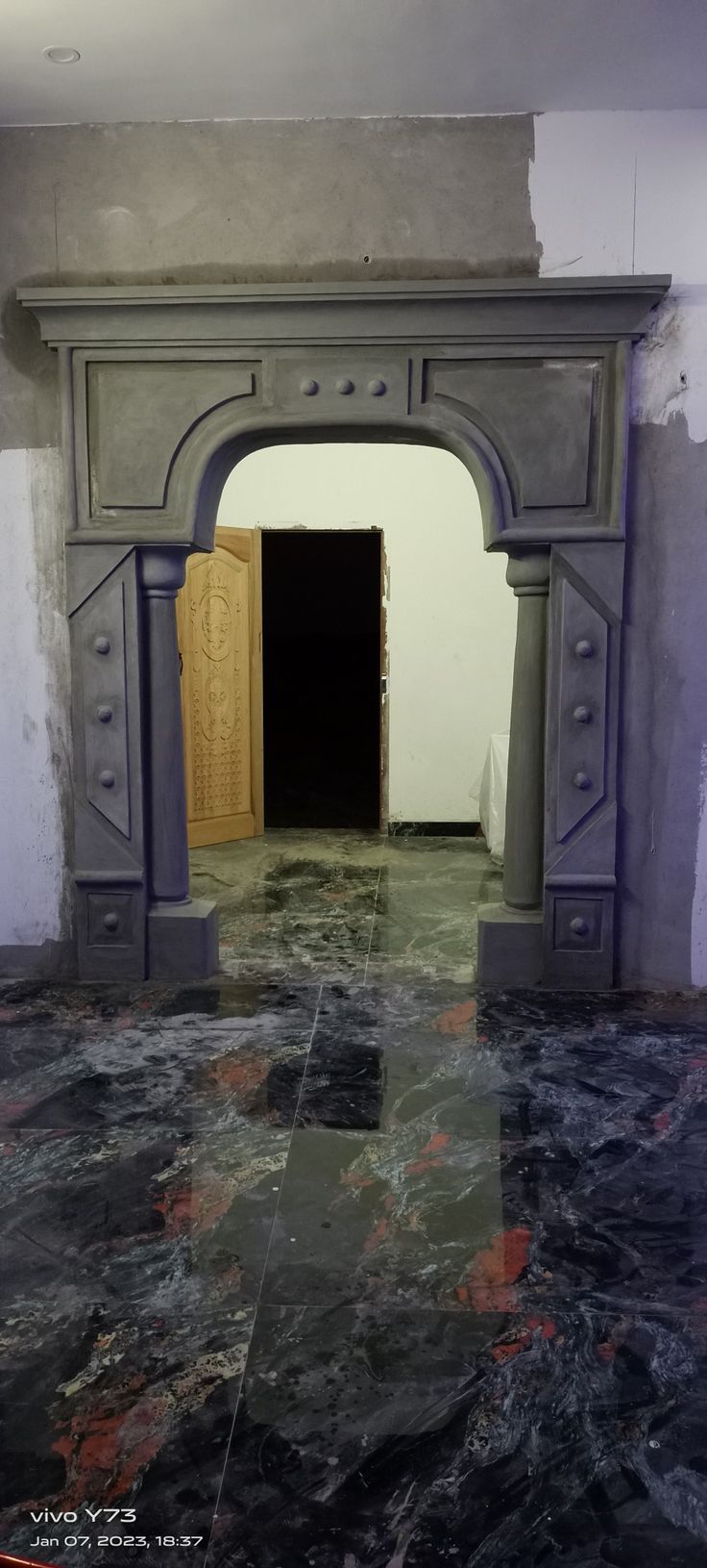 an entrance to a room with marble floors and walls, painted in grey tones on the wall