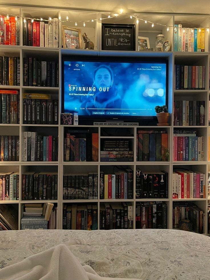 there is a television that is on in the bookshelf and it is full of books