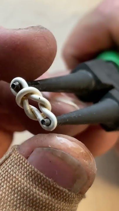 someone is cutting the end of a piece of wire with scissors