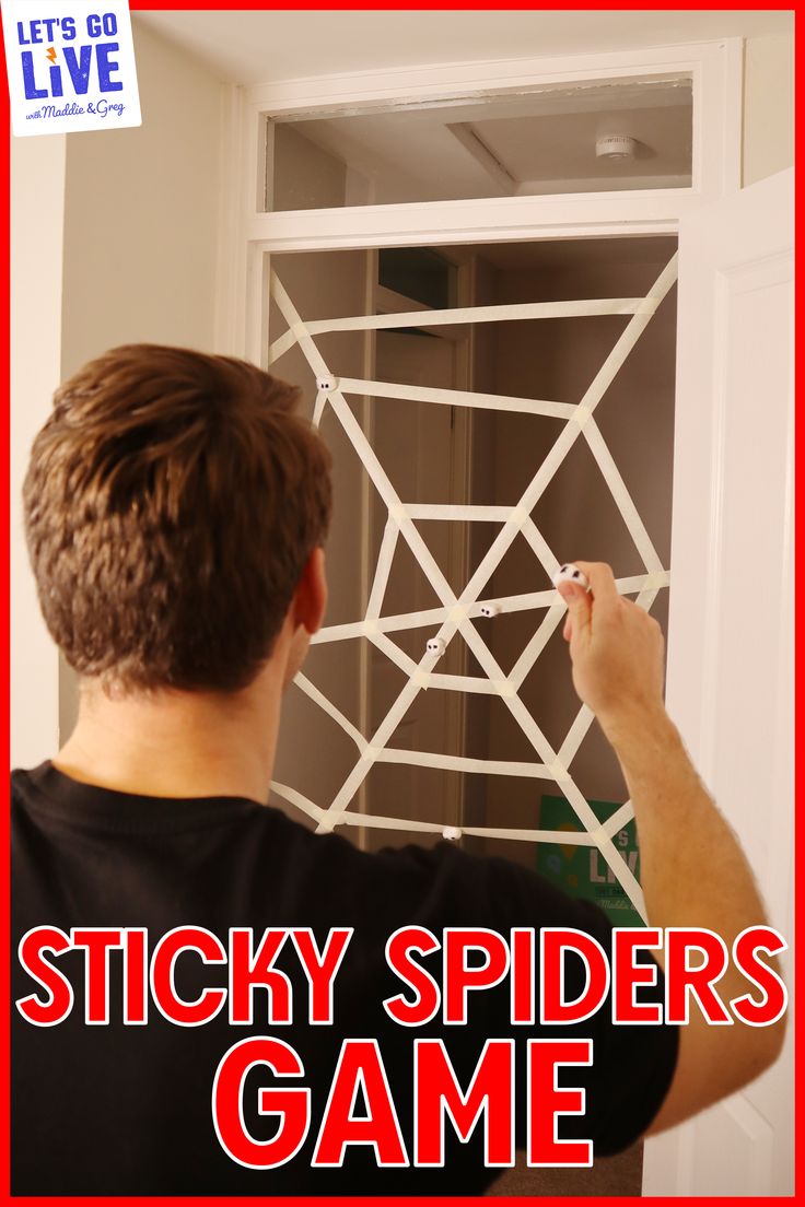 a man is painting the side of a door with stickers on it and writing, sticky spider's game