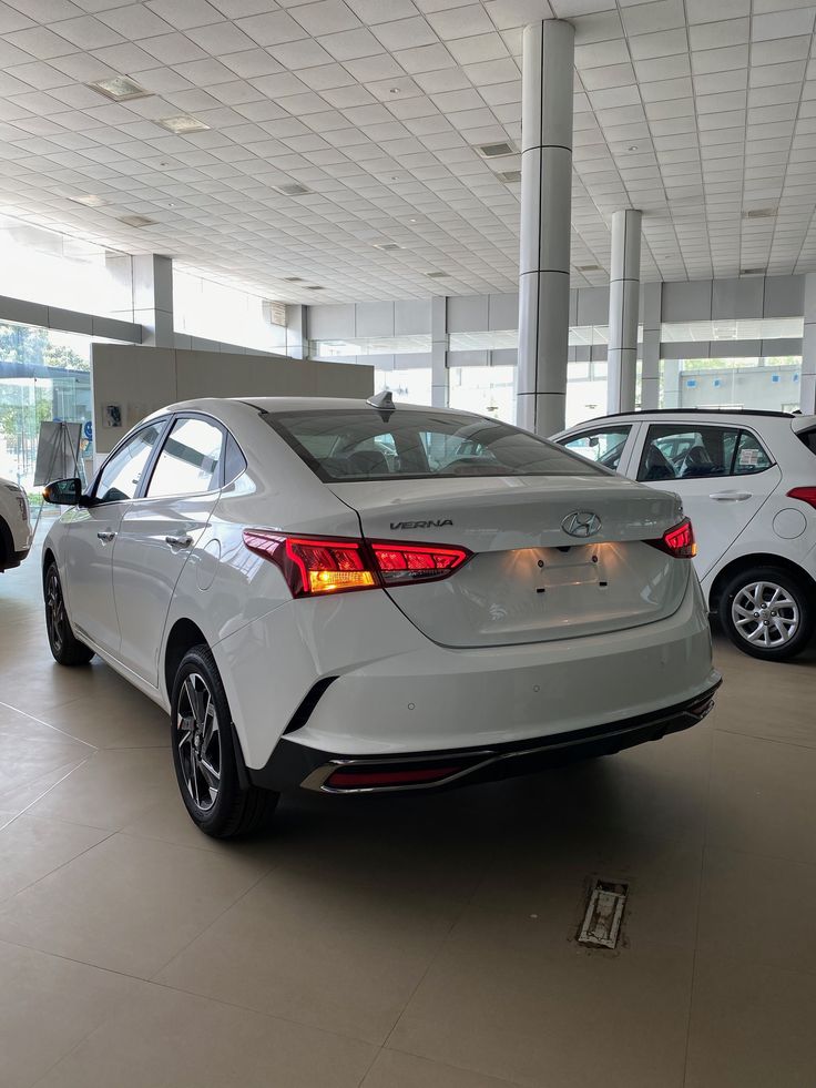 two white cars are parked in a showroom