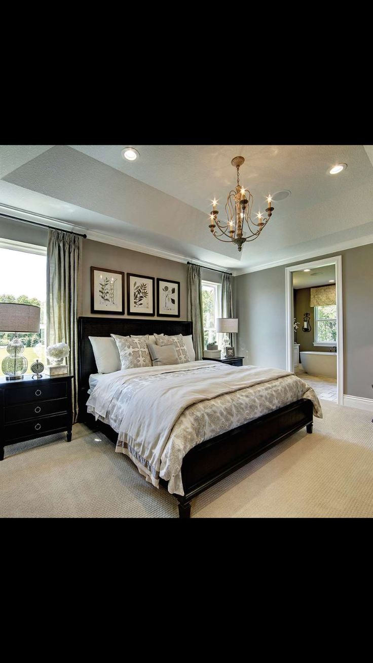 a bedroom with a large bed and chandelier hanging from it's ceiling