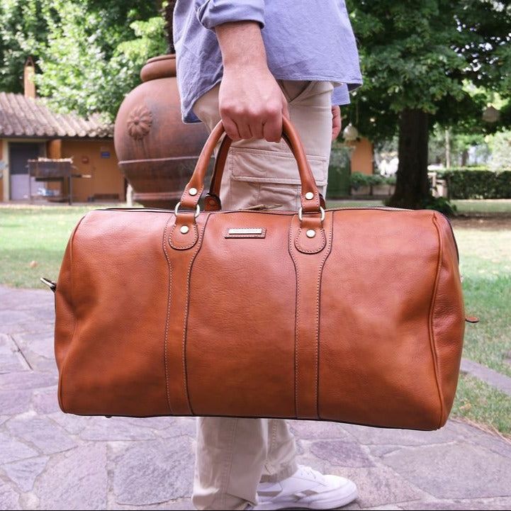 Pack for your next adventure in style with the Oslo Italian leather duffel bag.   Experience the timeless beauty of Italian craftsmanship with the Oslo cowhide weekender bag - the ultimate weekend companion for the modern traveler. Handcrafted in Italy from the finest full grain leather with a chic matte finish, this holdall exudes elegance and sophistication. With its spacious interior and soft structure, the Oslo is perfect for carrying all your essentials for a weekend getaway or a special occasion. The cotton lining and metal feet on the bottom offer added protection for your belongings, while the detachable and adjustable leather shoulder strap allows for comfortable carrying. The Oslo also features brushed brass-toned or silver-toned hardware (depending on the color of the bag), incl Classic Leather-lined Luggage For Weekend Trips, Luxury Duffle Bag With Leather Handles For Weekend Trips, Luxury Cognac Travel Bag For Weekend Trips, Luxury Cognac Weekender Bag For Everyday, Elegant Leather Duffle Bag For Business Trips, Luxury Cognac Duffle Bag For Travel, Classic Travel Bag With Leather Lining For Weekend Trips, Classic Leather Duffle Bag For Weekend Trips, Elegant Cognac Duffle Bag For Travel