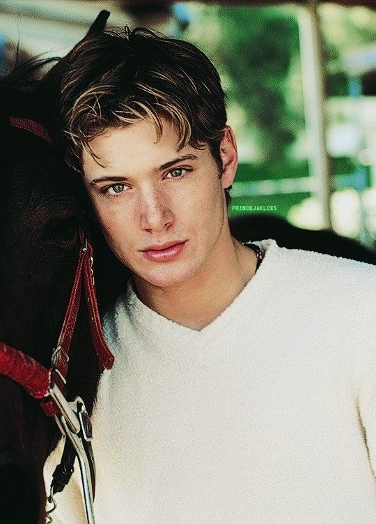 a young man standing next to a horse