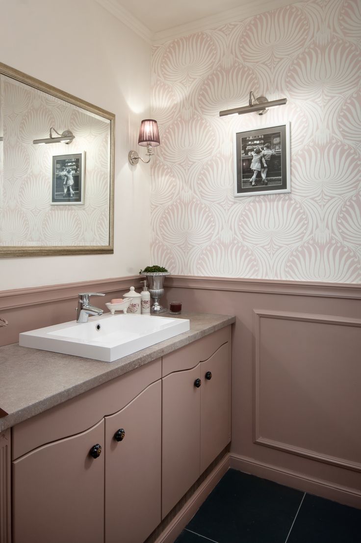 a bathroom with a sink and mirror next to a wallpapered wall behind it