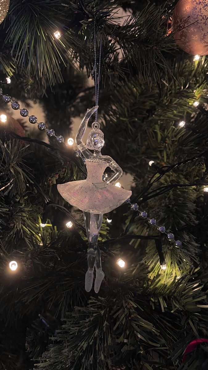 a glass ornament hanging from a christmas tree with lights on it's branches