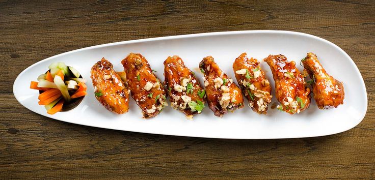 a white plate topped with chicken wings covered in sauce