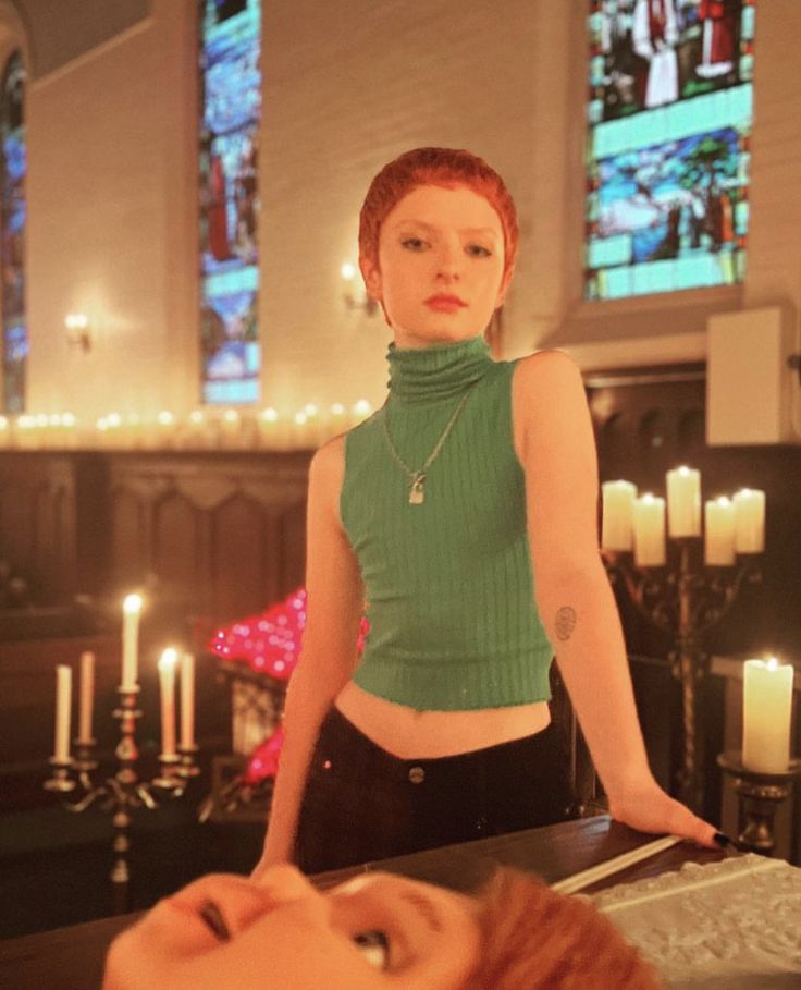 a woman with red hair standing in front of candles