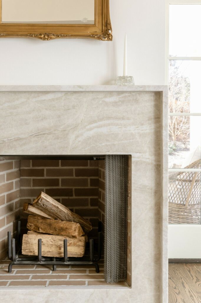 a fire place in a living room with a painting on the wall and wood stacked up