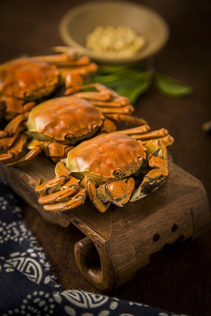 three crabs are sitting on a wooden board