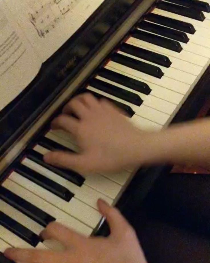 a person is playing the piano with their hand on it's keyboard and sheet music behind them