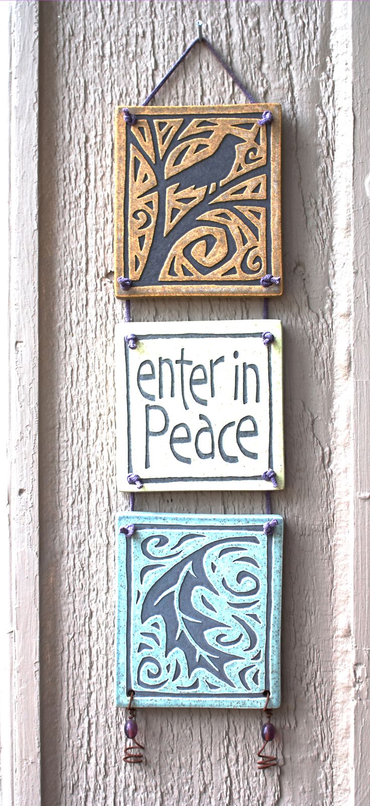 two wooden signs hanging on the side of a building with metal bells attached to them