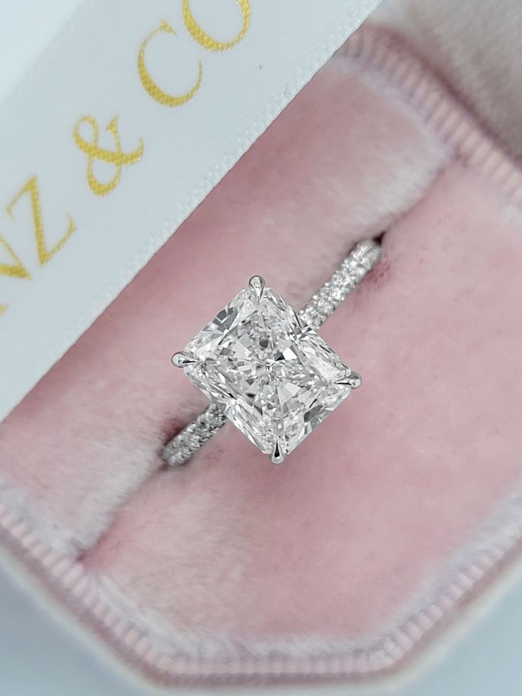 an engagement ring with a princess cut diamond on it's side in a pink velvet box