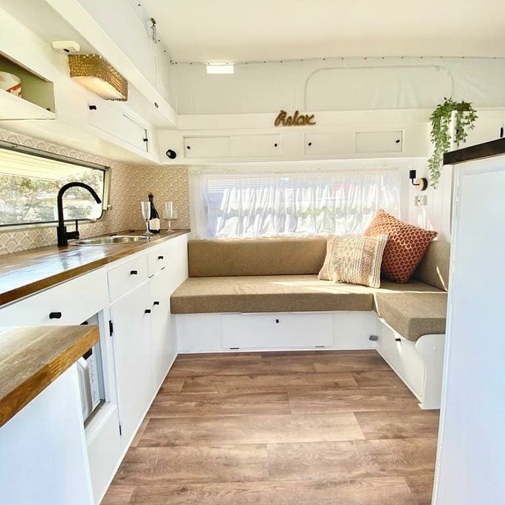 the interior of a camper with wood flooring and white cabinets, including a couch