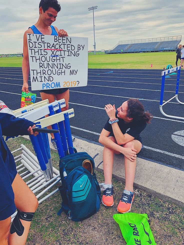 a woman sitting on the side of a road next to a man holding a sign